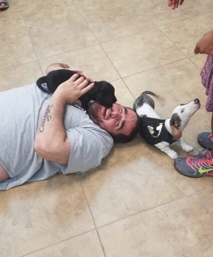 Petland Texas picture of Disability Achievement Center patients playing with cute Petland puppies on the floor.