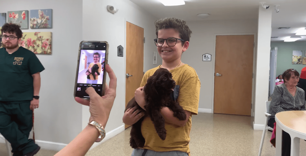 Petland Texas picture of child holding a cute petland puppy and taking a selfie photo.