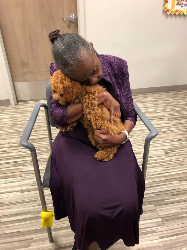 Petland Texas picture of patient from Memorial Adult Day Care holding cute Petland puppy.