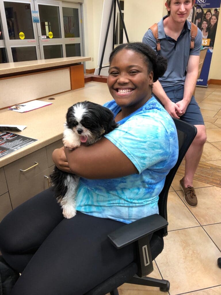 Petland Texas picture of Nova Campus student holding a cute Petland puppy at NSU campus.