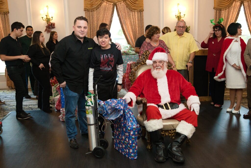 Petland Texas picture of Miami Power Team child and Petland owner posing with Santa Claus at community event.