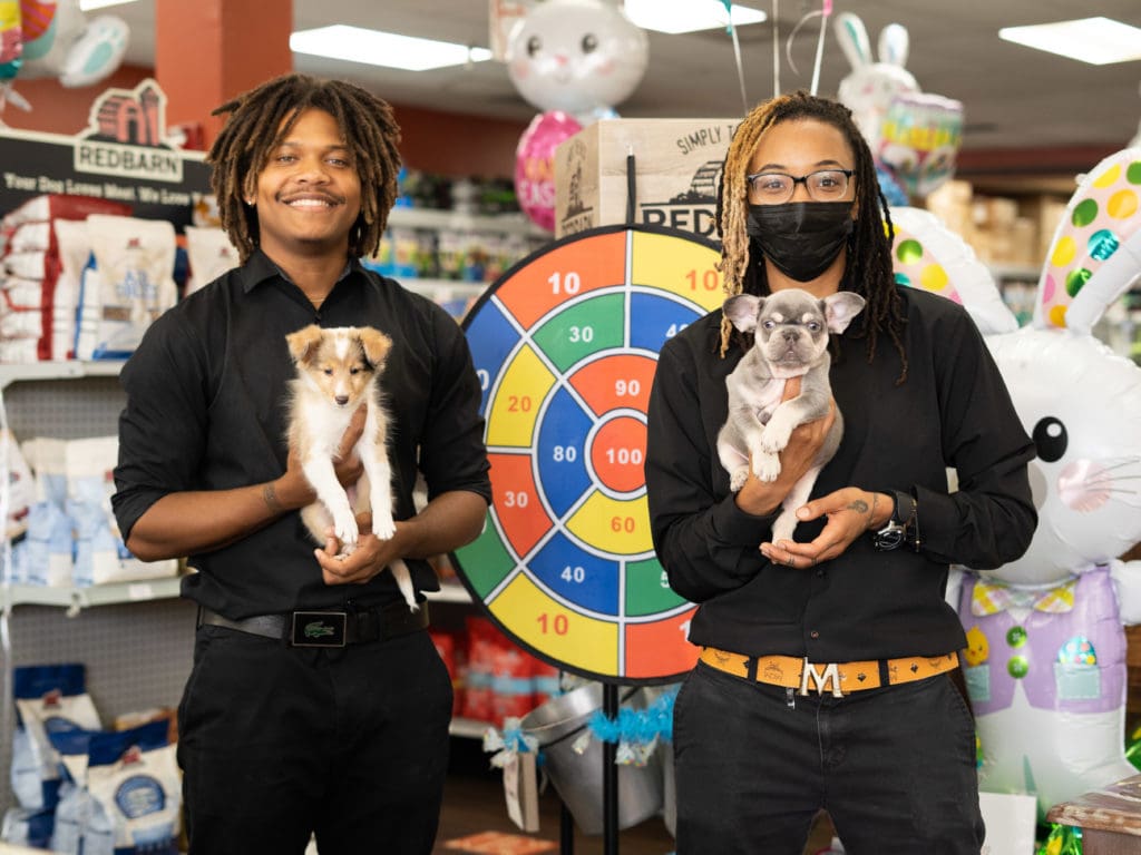 Two Petland employees holding cute puppies for sale while standing in a Petland Texas store for the National Pet Day Carnival.
