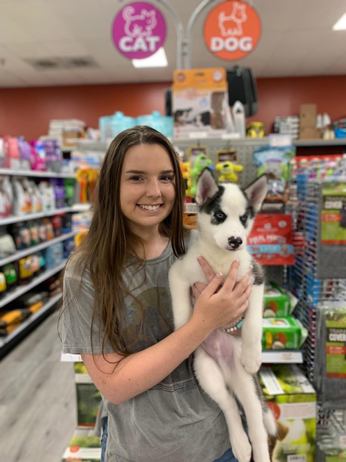 A woman holding a black-and-white puppy inside a Petland store