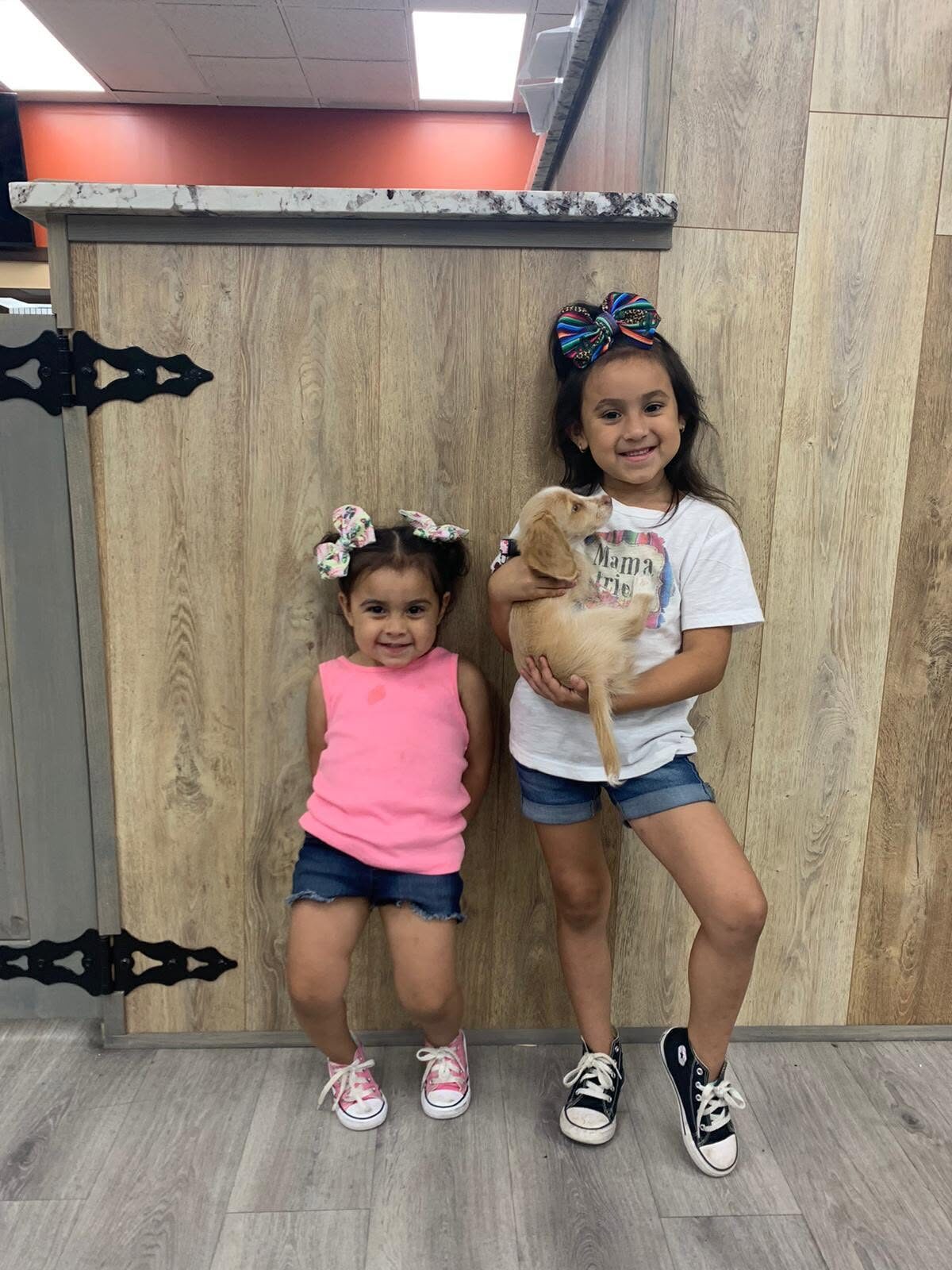 Two children standing together with a tan puppy